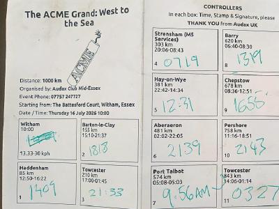 Completed brevt card for ACME Grand cycling event showing 12 control points with handwritten arrival/departure times in green ink, distance totals per section, and contact details for Audax UK.