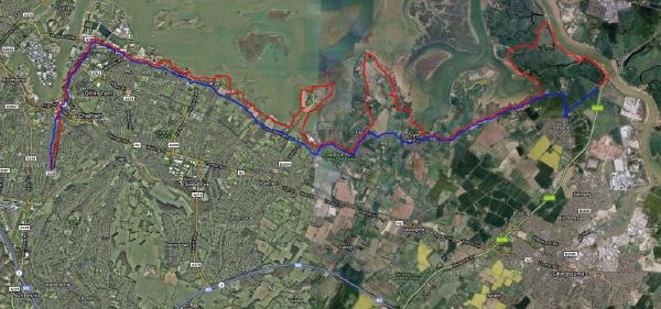 An aerial satellite map view showing a cycling route marked with colored lines blue, red, and purple sections that traces a path through the Medway estuary area near Chatham, passing through various locations including Upchurch, Lower Halstow, and extending toward the Isle of Sheppey, with the route clearly marked against the green landscape, waterways, and urban areas.