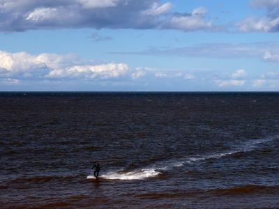Kite Surfer in Birchington. The point at which I turned into the wind. Kitesurfer gliding across choppy sea under a bright, cloudy sky.
