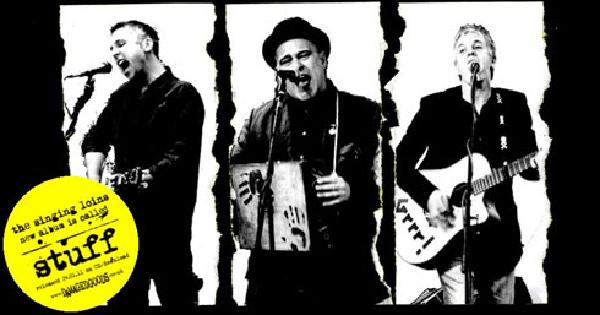 A black and white promotional image showing three musicians performing, presented in a torn paper aesthetic with jagged white borders against a black background. From left to right: a vocalist singing into a microphone, a central performer wearing a black hat and holding what appears to be a washboard or similar percussion instrument, and a guitarist playing an acoustic guitar. A yellow circular badge or sticker in the bottom left contains text that appears to reference The Singing Loins and includes the word stuff prominently displayed.