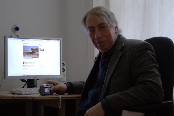 Peter Cook sitting in front of my computer screen and looking into the camera