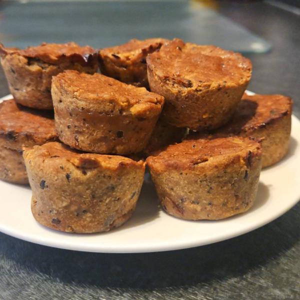 Plate stacked with several small golden-brown baked pear on a dark kitchen worktop.